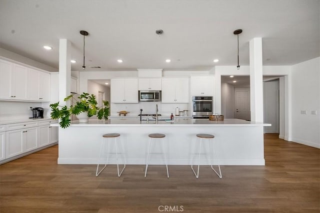 kitchen featuring appliances with stainless steel finishes, light countertops, white cabinetry, and wood finished floors