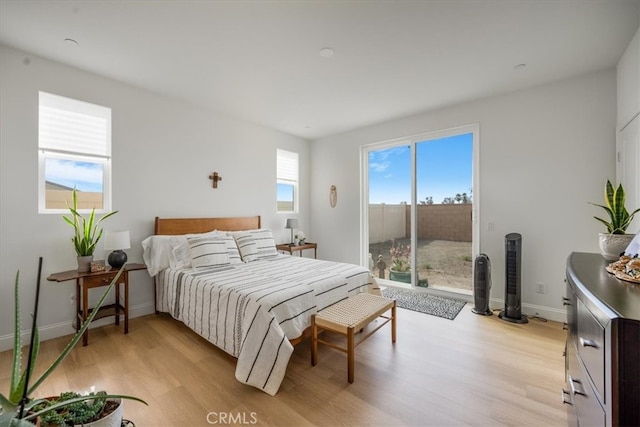 bedroom with light wood-style floors, access to outside, and baseboards