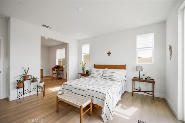 bedroom featuring light wood-style flooring, visible vents, and baseboards