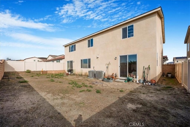 back of house with a fenced backyard, central AC, and stucco siding