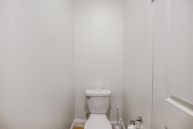 bathroom featuring baseboards and toilet