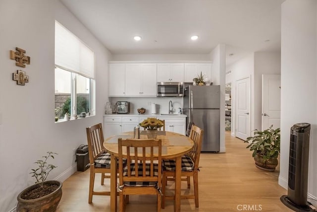 dining room featuring baseboards, light wood finished floors, and recessed lighting