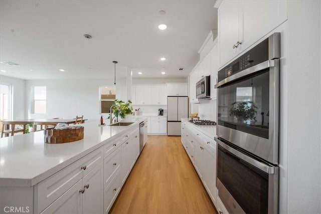 kitchen featuring light wood-style floors, white cabinetry, appliances with stainless steel finishes, and light countertops