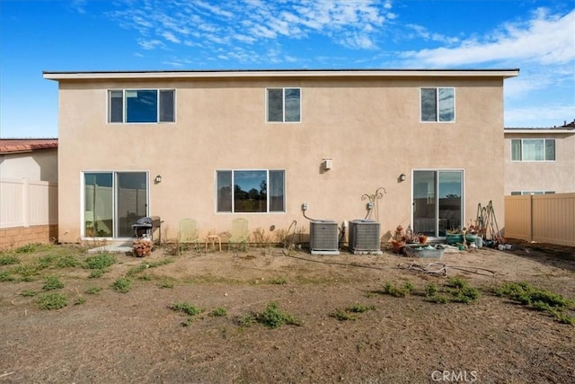 back of property featuring central air condition unit, fence, and stucco siding