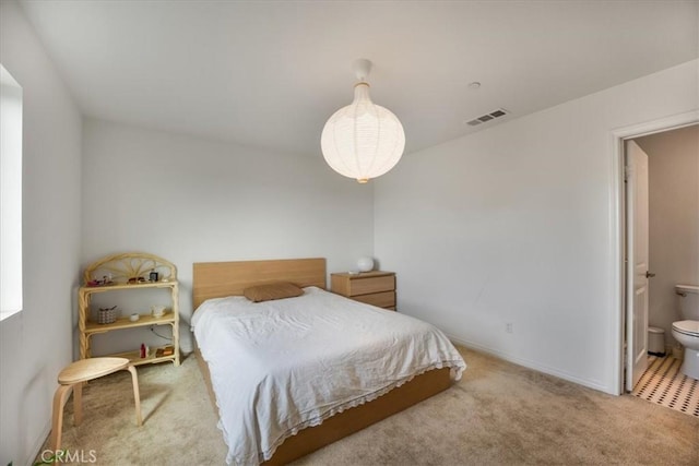 carpeted bedroom with visible vents, connected bathroom, and baseboards