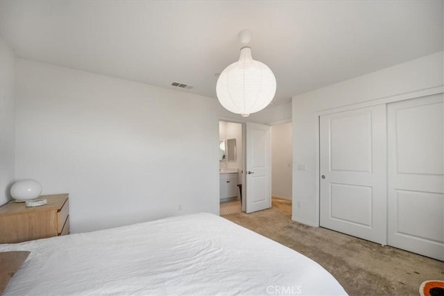 carpeted bedroom featuring visible vents, a closet, and ensuite bathroom