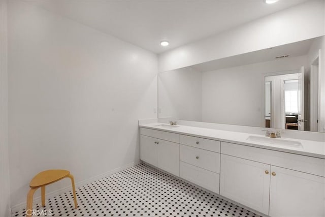 bathroom featuring double vanity, a sink, baseboards, and tile patterned floors