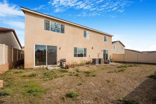 rear view of house featuring central AC unit, a fenced backyard, and stucco siding