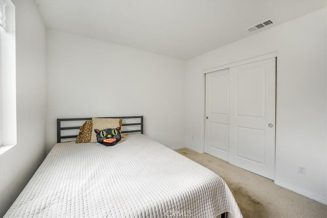 bedroom featuring light carpet, a closet, visible vents, and baseboards