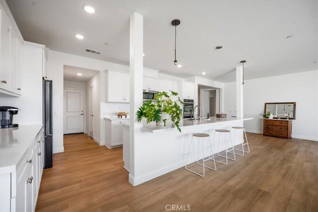 kitchen with recessed lighting, light countertops, visible vents, light wood-style flooring, and white cabinetry