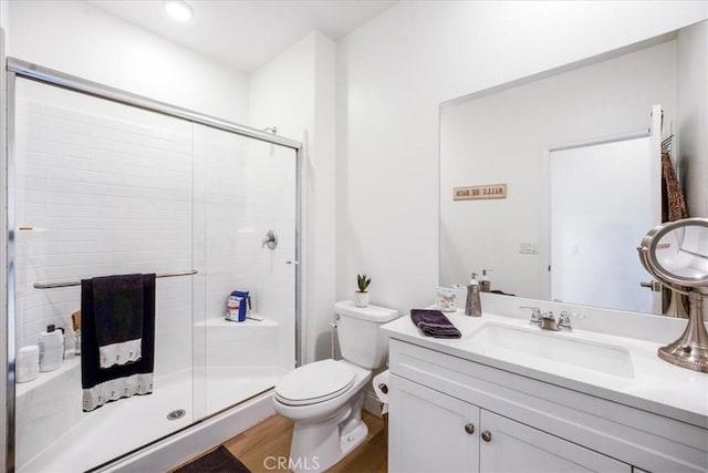 full bath with vanity, wood finished floors, a shower stall, and toilet