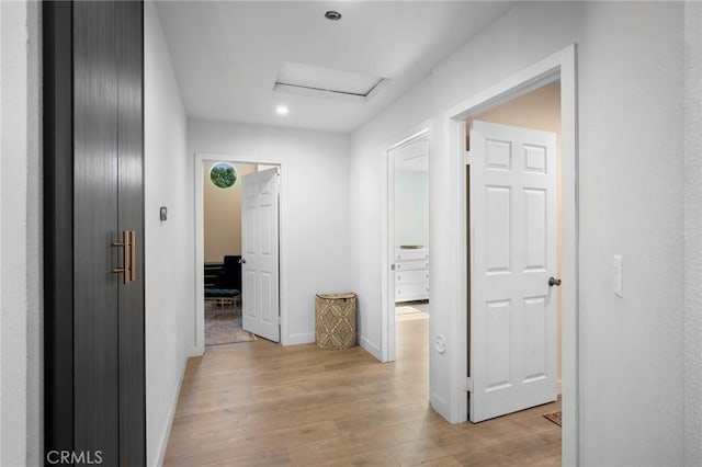 corridor with light wood-type flooring, attic access, baseboards, and recessed lighting