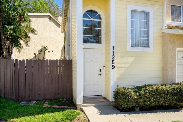 view of exterior entry featuring fence and stucco siding