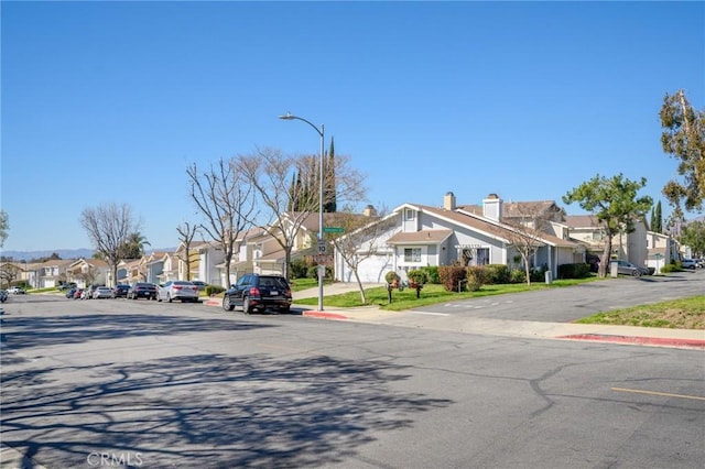 view of street featuring a residential view, curbs, sidewalks, and street lights