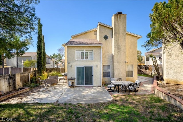 rear view of property with a fenced backyard, a patio, and stucco siding