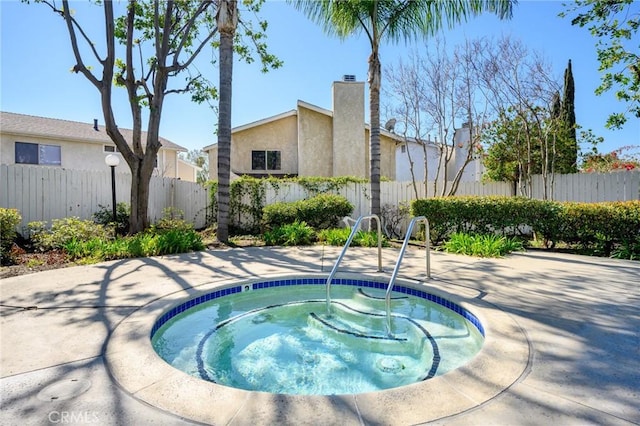 view of swimming pool with a community hot tub and fence