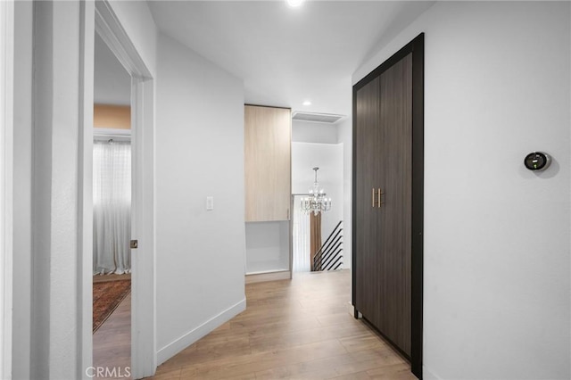 hallway featuring light wood finished floors, an inviting chandelier, recessed lighting, and baseboards