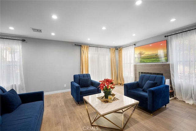 living room with recessed lighting, a fireplace, visible vents, baseboards, and light wood-style floors