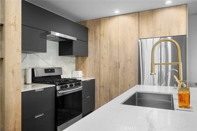 kitchen with light countertops, appliances with stainless steel finishes, ventilation hood, and dark cabinetry