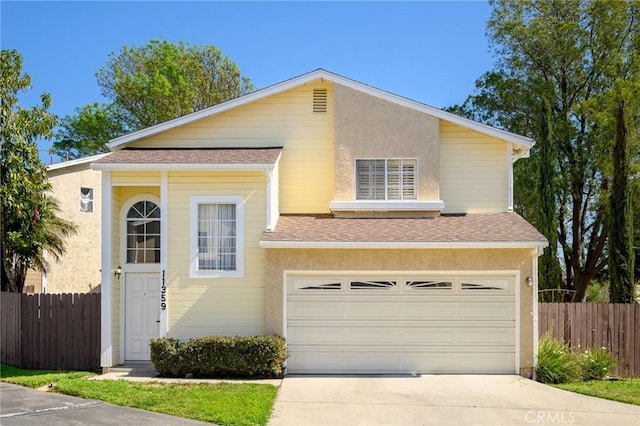 traditional home with driveway, a shingled roof, an attached garage, fence, and stucco siding