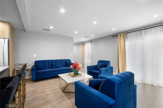 living room with a wealth of natural light, light wood-style floors, visible vents, and recessed lighting