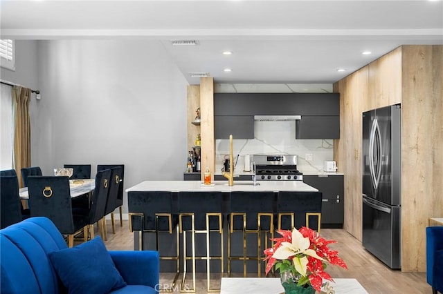 kitchen featuring visible vents, decorative backsplash, stainless steel appliances, light countertops, and light wood-type flooring