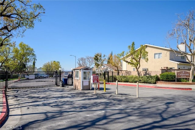 view of road featuring a gated entry, curbs, a residential view, a gate, and street lighting