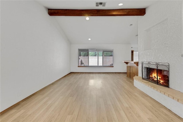 unfurnished living room with a fireplace, beamed ceiling, visible vents, and wood finished floors