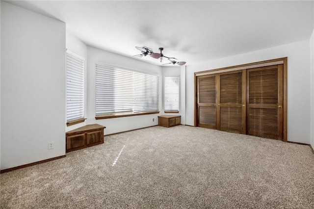 unfurnished bedroom with carpet, a closet, ceiling fan, and baseboards