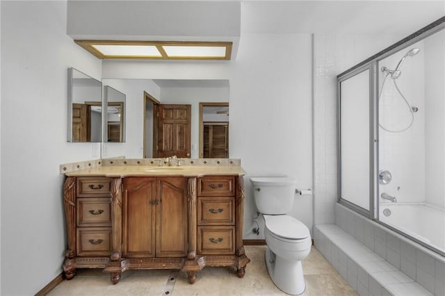 bathroom featuring baseboards, tiled shower / bath, toilet, and vanity