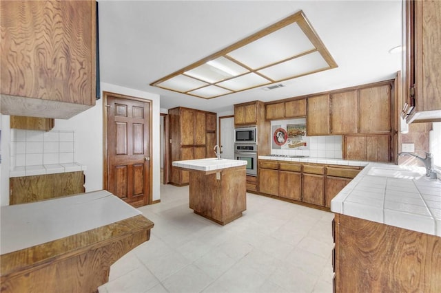 kitchen featuring visible vents, tile counters, appliances with stainless steel finishes, and a sink