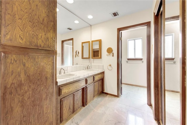 bathroom featuring double vanity, a sink, visible vents, and baseboards