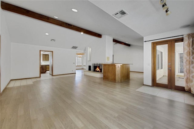 unfurnished living room featuring french doors, visible vents, lofted ceiling with beams, light wood-type flooring, and a warm lit fireplace