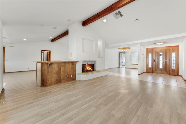 unfurnished living room with high vaulted ceiling, visible vents, a brick fireplace, beam ceiling, and light wood finished floors