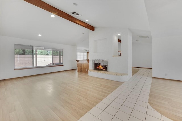 unfurnished living room featuring visible vents, lofted ceiling with beams, wood finished floors, a brick fireplace, and recessed lighting