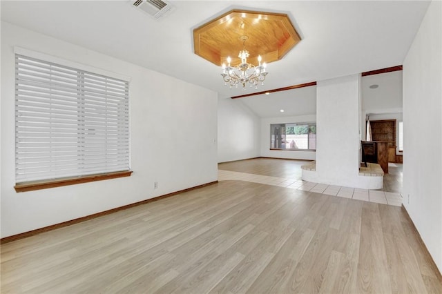 interior space featuring a notable chandelier, lofted ceiling, visible vents, wood finished floors, and baseboards