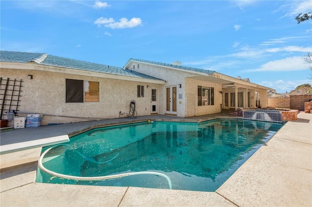 view of pool featuring french doors, a pool with connected hot tub, a patio area, fence, and a diving board