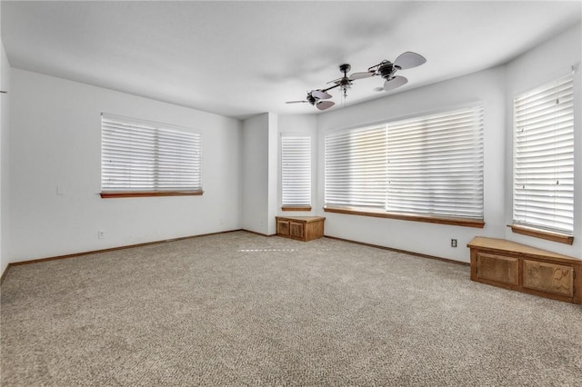 carpeted spare room with plenty of natural light, baseboards, and ceiling fan