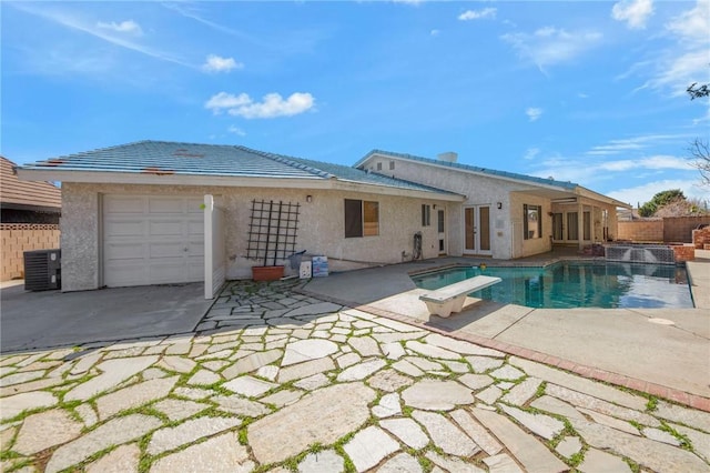 back of house featuring a garage, fence, french doors, a fenced in pool, and stucco siding