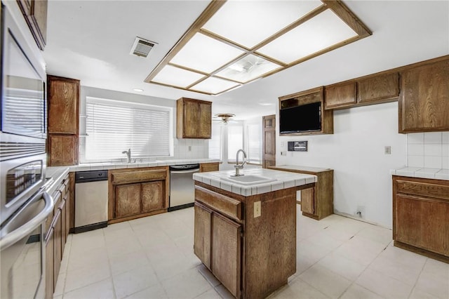 kitchen featuring a sink, tile countertops, decorative backsplash, and stainless steel dishwasher