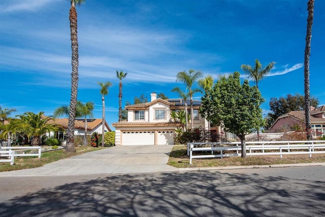 view of front of house featuring a fenced front yard, solar panels, driveway, a tiled roof, and a chimney