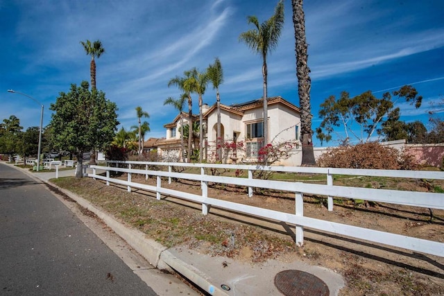 view of front of home featuring a fenced front yard, roof mounted solar panels, and stucco siding