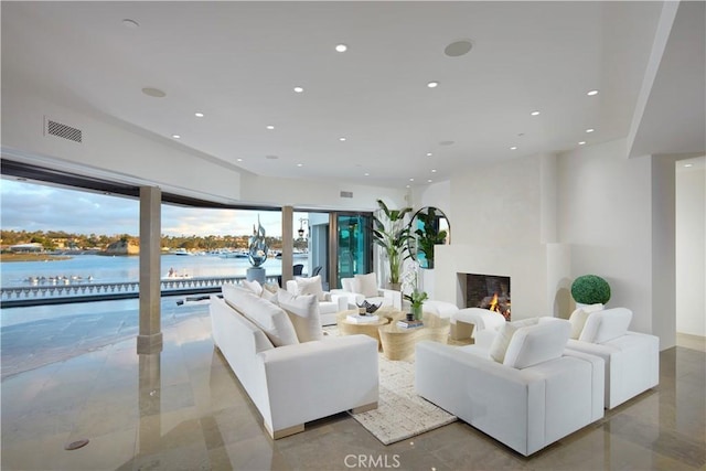 living area featuring a water view, a fireplace, visible vents, and recessed lighting