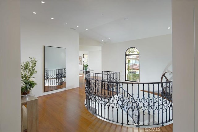 hallway featuring lofted ceiling, wood finished floors, an upstairs landing, and recessed lighting