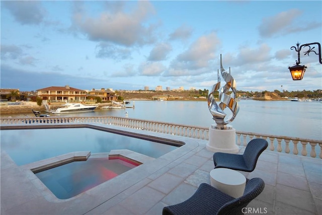 view of swimming pool with a water view and an in ground hot tub