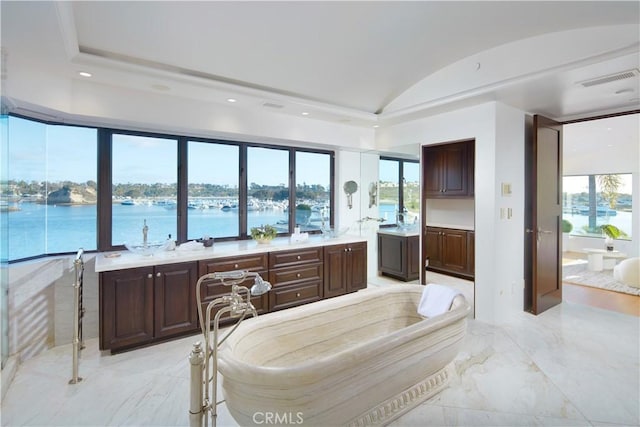 bedroom with marble finish floor, lofted ceiling, multiple windows, and a water view