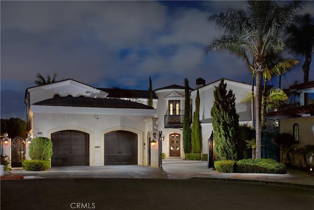 mediterranean / spanish house featuring driveway, a garage, french doors, and stucco siding