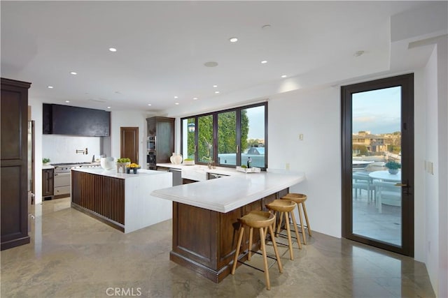 kitchen with light countertops, a kitchen bar, recessed lighting, a center island, and double oven