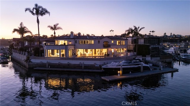 rear view of house featuring a balcony, a water view, and a chimney
