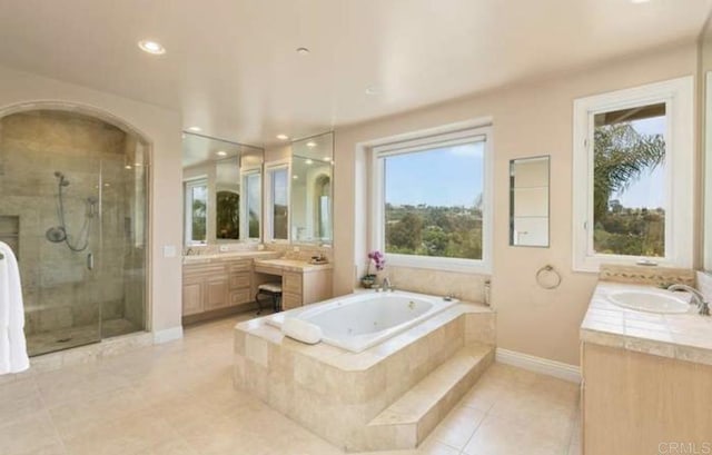 full bath with baseboards, two vanities, a sink, a shower stall, and a bath